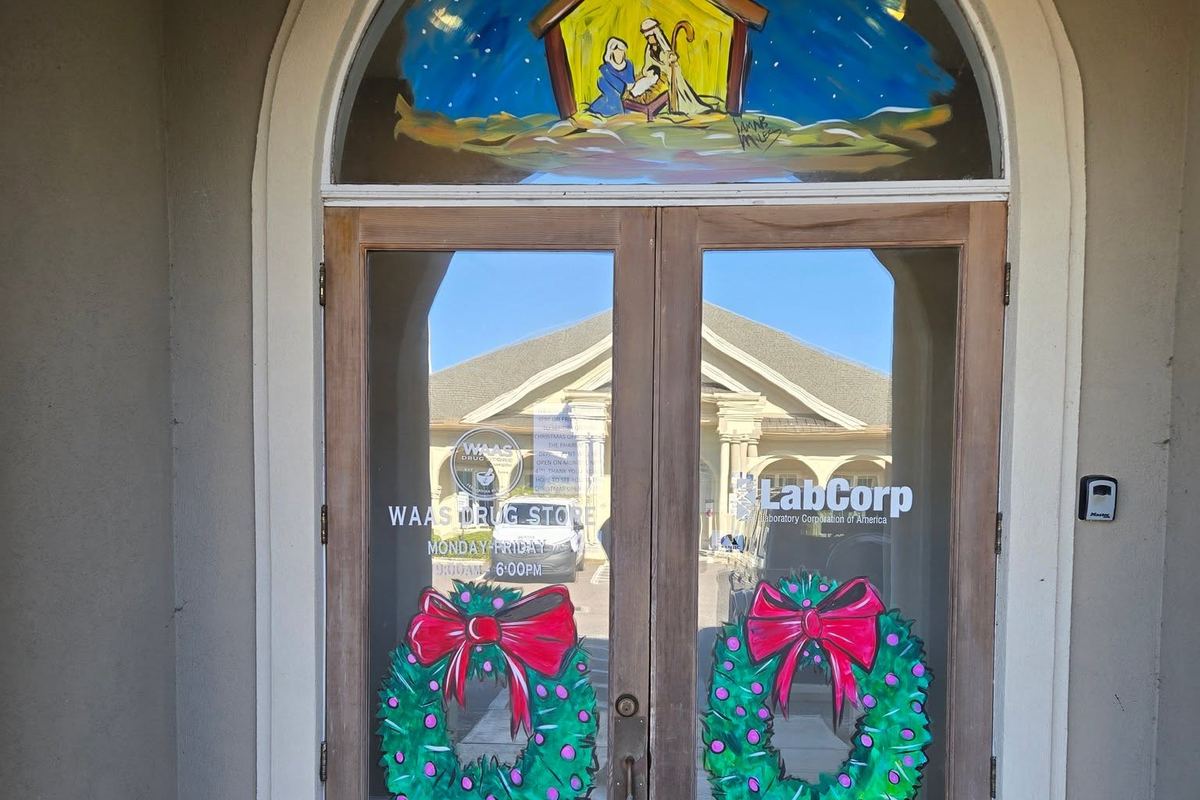 Wreaths on the front doors and a painted nativity above the entrance at Waas Drug Store