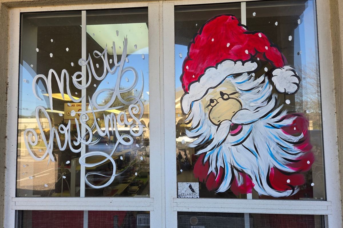 Hand-painted Merry Christmas and Santa artwork on the storefront windows