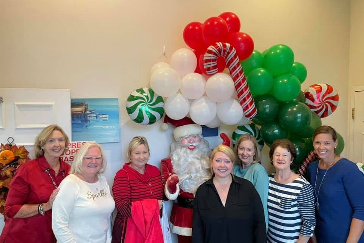 The Waas Drug Store team with Santa in front of a red and green balloon arch on open house day