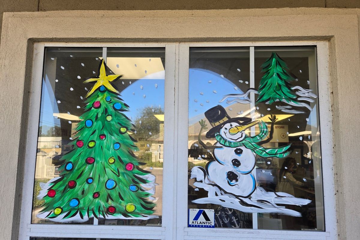 Hand-painted Christmas tree and snowman artwork on the storefront windows